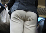 An erotic image in which a pantsuit bites into the big buttocks of an office lady