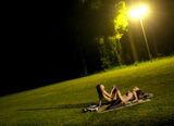 Night erotic image of lesbian play outdoors bathed in lights at night